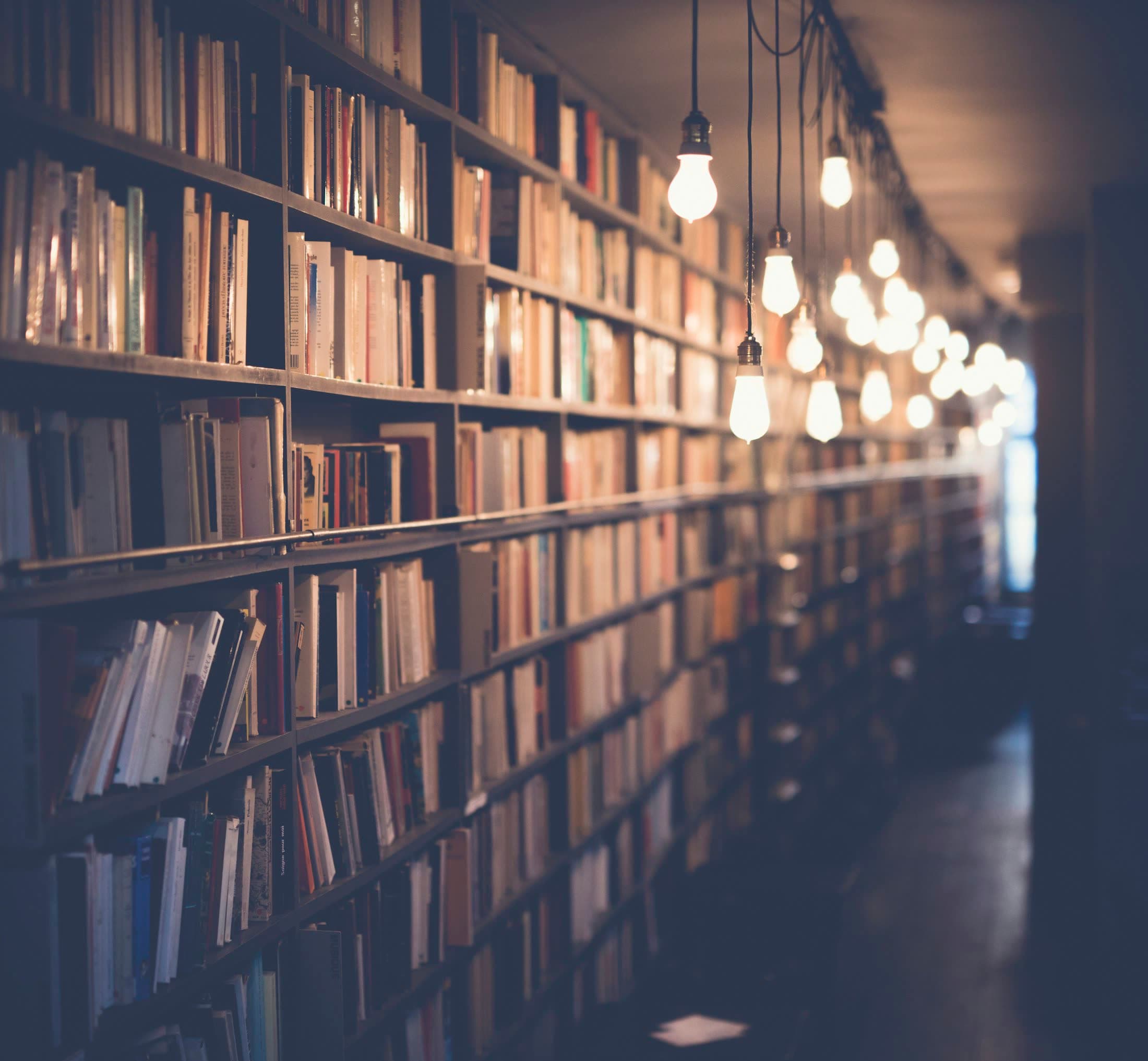 A warm library aisle lit by hanging bulbs