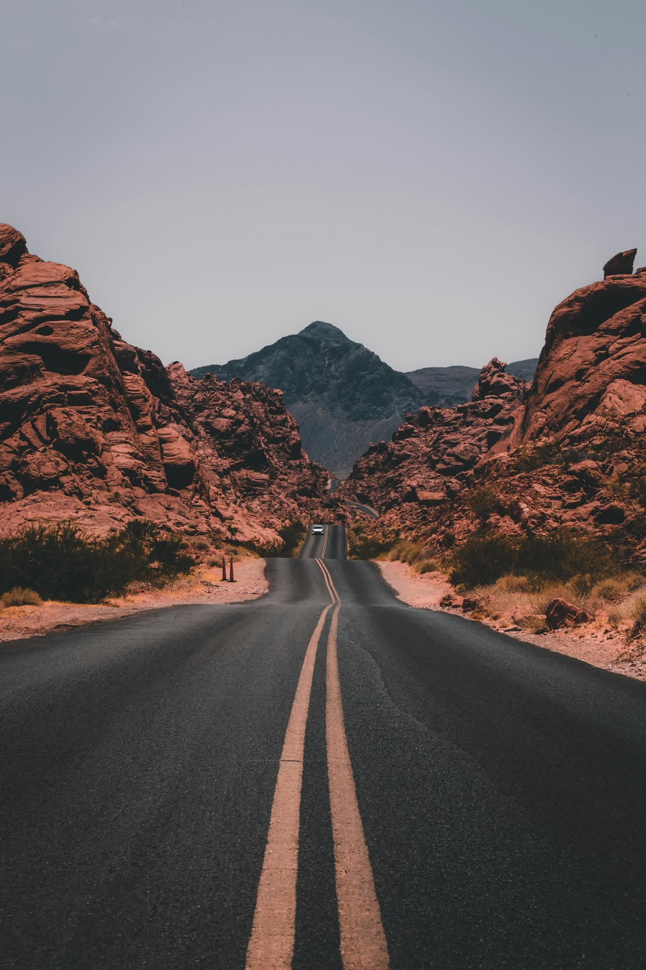 An open road winding through a red-rock canyon toward a distant mountain
